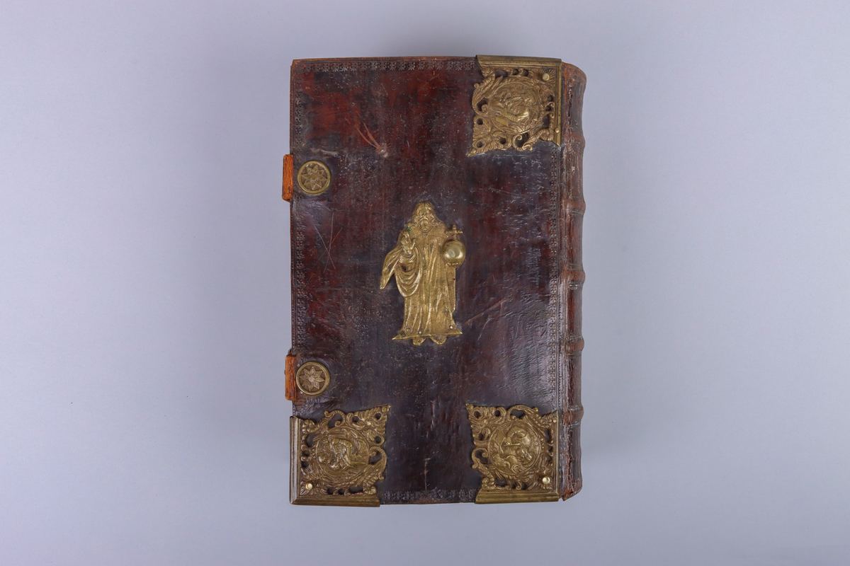Bibel, marmorerat skinnband med upphöjda bind, dekorerad rygg. På framsida beslag i genombruten mässing med olika apostlar mitt på Moses med stentavlor. Omtag och lås med Karl XII monogram. Bibeln rymmer flertalet planscher och porträtt samt utvik med kartor.