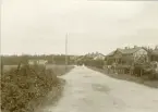 Bruksväg, troligen från Gysinge, med byggnader längs vägen.