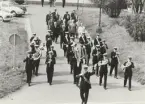 Musikkår följs av officerare och civila.
