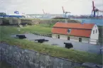 Nya Älvsborgs fästning, mur med tre kanoner, varvskranar i bakgrunden.