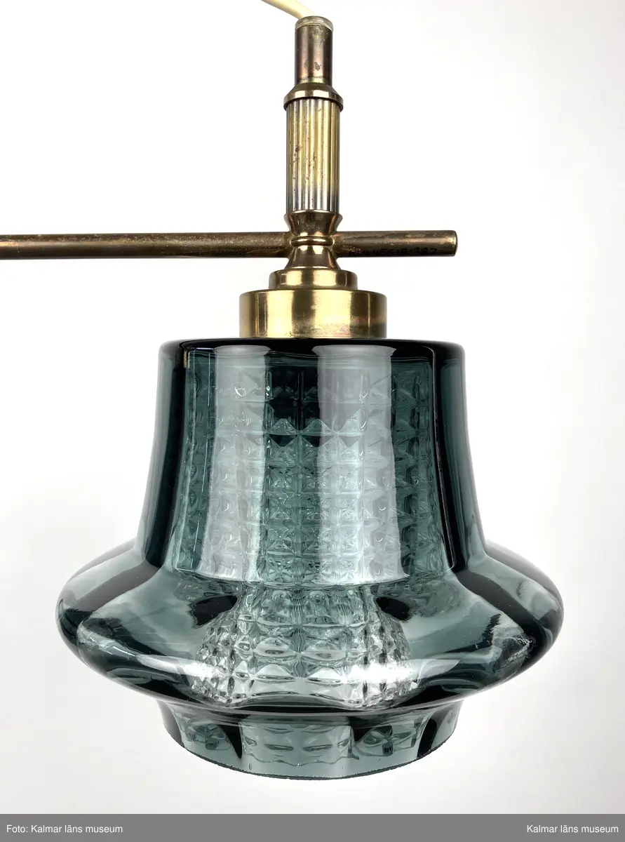 KLM 45619:387. Lampa, taklampa. Mässingstativ med tre hållare med glaskupor. De inre kuporna av genomskinligt glas med rutmönsterverkan. De yttre glaskuporna i gröngrå nyans med något som liknar ett brätte nedtill. Vit plastsladd med mässingkupa för att dölja kontakt.