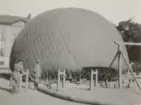 Kapten Yngve Stiernspetz står vid en ballong som fylls med gas. 1930-tal.