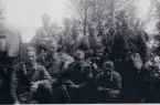 Grupp beväpnad med karbiner poserar vid en klövjad häst, Värmland 1943.