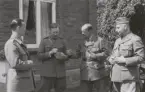 Officerare vid signaltrupperna diskuterar utanför hus, uniform m/1939.