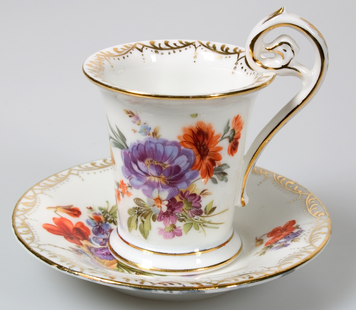 Sex kaffekoppar med fat, av vitt porslin. Guldkantsdekor. Blommålning i olika motiv i rosa, orange, blått, grönt, lila, gult mm. Av märket Meissen.


