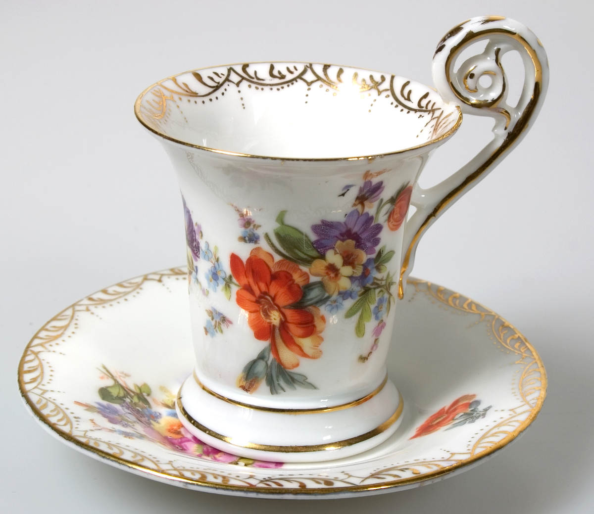 Sex kaffekoppar med fat, av vitt porslin. Guldkantsdekor. Blommålning i olika motiv i rosa, orange, blått, grönt, lila, gult mm. Av märket Meissen.


