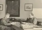 Infanterist och en man ur trängen sitter vid skrivbord, expeditionstjänst, uniform m/1939.