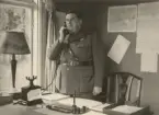 Infanterist talar i telefon vid skrivbord, expeditionstjänst, uniform m/1939.
