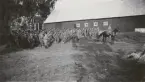 Trupp uppställd vid ladugård.
