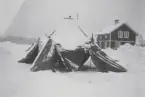 Översnöat tält vid en stuga.