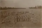 Hälsinge regemente I 14 Mohed. Arbetsklädda män uppställda i en grusgrop.