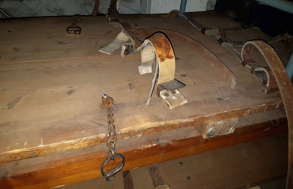 Reimseng i tre sammenføyd med kraftige jernnagler. Lave, kraftige ben. I fotenden finnes to hull, der en lenke kan tres igjennom og festes (Lenken mangler, kan være NRM.09014). Det finnes heller ingen reim til å feste føttene med. Et regulerbart belte i lær og lerretsstoff er montert horisontalt i midjehøyde, tredd gjennom to jernfester. Et håndjern er montert i midjehøyde på hver side. To lærbelter er festet i hodeenden. Disse skal føres vertikalt ned på hver side av fangens hode og overkropp, og har løkker i endene, så de kan festes i et horisontalt belte over brystet. Brystbeltet er festet i slisser i sengebunnen. Lemmen har ingen bevart polstring, madrass e.l.