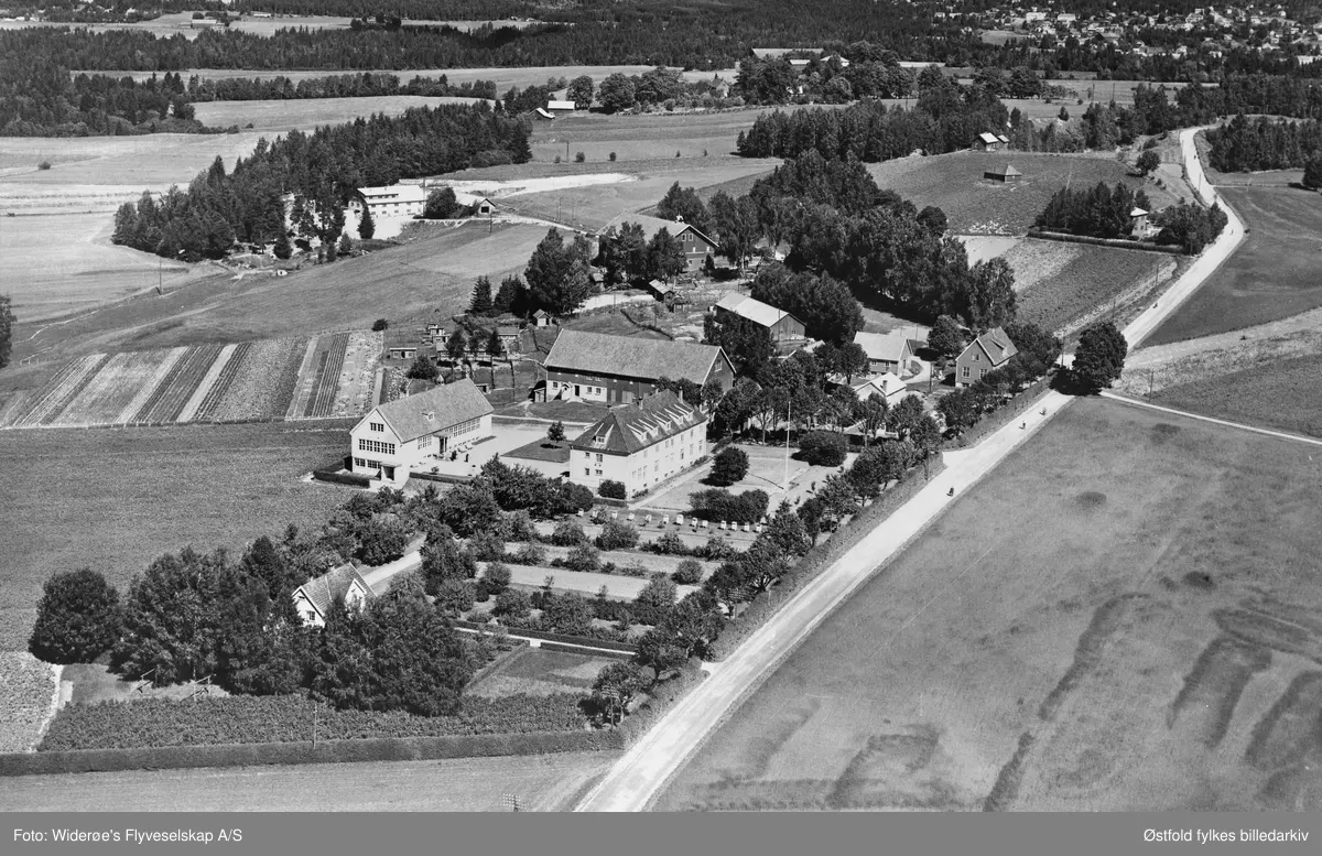Skråfoto av Haga Jordbruksskole i Eidsberg ca. 1950-50. Eier Østfold Fylke, kjøpt i 1917. Internatbygning, driftsbygning, verksted og stabbur1918, lærer- boliger 1938,1939 og 1954, 2 veksthus 1948, høneshus 1953, m.m.
Bilde 2 limt på bakside av flyfoto er bilde av en katt og en mus, ukjent opphav.