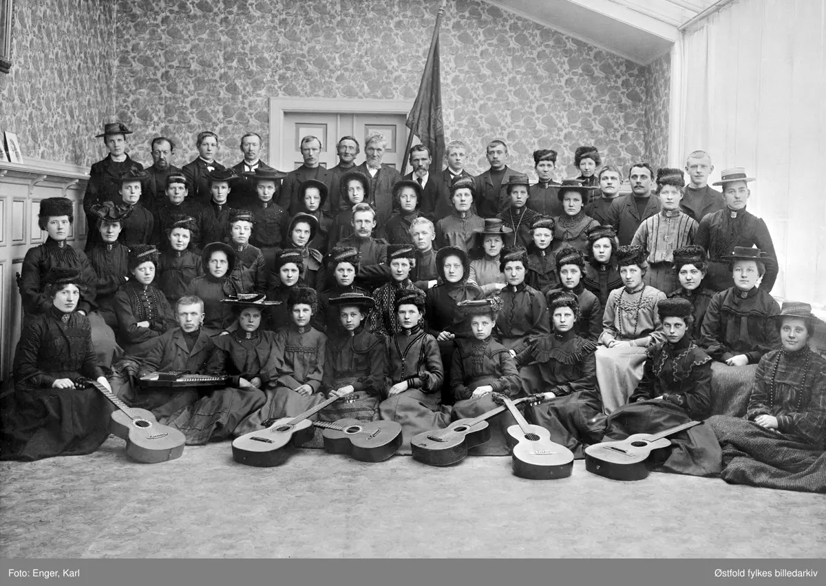 Gruppebilde av Frelsesarmeens musikkorps i Tistedal 1906-07. Fra korpsets 10-årsjubileum.
Sittende på gulvet fra venstre: 
nr. 2. Wilhelm Kaspersen med zither/siter, nr. 8 Jenny Jensen, nr. 9. Anna Lie.
Sittende på stol:
nr. 1. Julie Floberg, nr. 7 Hilda Østhaug, nr. 8 Dagny Andersen. 
Midt i 3. rekke, sittende på stol: Offiser Olaf Vestby.
Første stående rekke: 
nr. 1 Tomine Arvesen, nr. 2. Amanda Andersen. 
Bakerste rekke: 
nr. 1 Marie Fjeld, nr. 13 Viktor Andersen.
