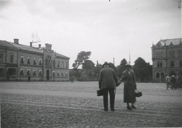 Varbergs torg med Rådhuset till vänster och Sparbankshuset till höger i bakgrunden. Kvinnan som drar i mannens käpp kallades för "Smissa". I rådhusbyggnaden fanns även polisstation och telegraf, därav ställningen på taket för ledningarna.
