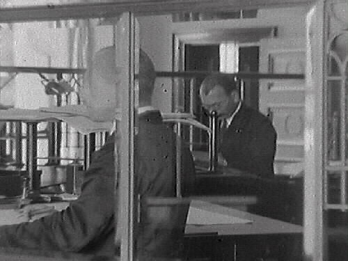 Interiörbild från expeditionslokalen i Varbergs sparbank. Mannen bakom disk till höger heter Arvid Adolfsson. Fönstren i bakgrunden vetter mot öster. Till en början hade man banklokaler på bottenvåningens östra del medan Hallandsbanken och Göteborgsbanken hyrde lokaler i den västra.