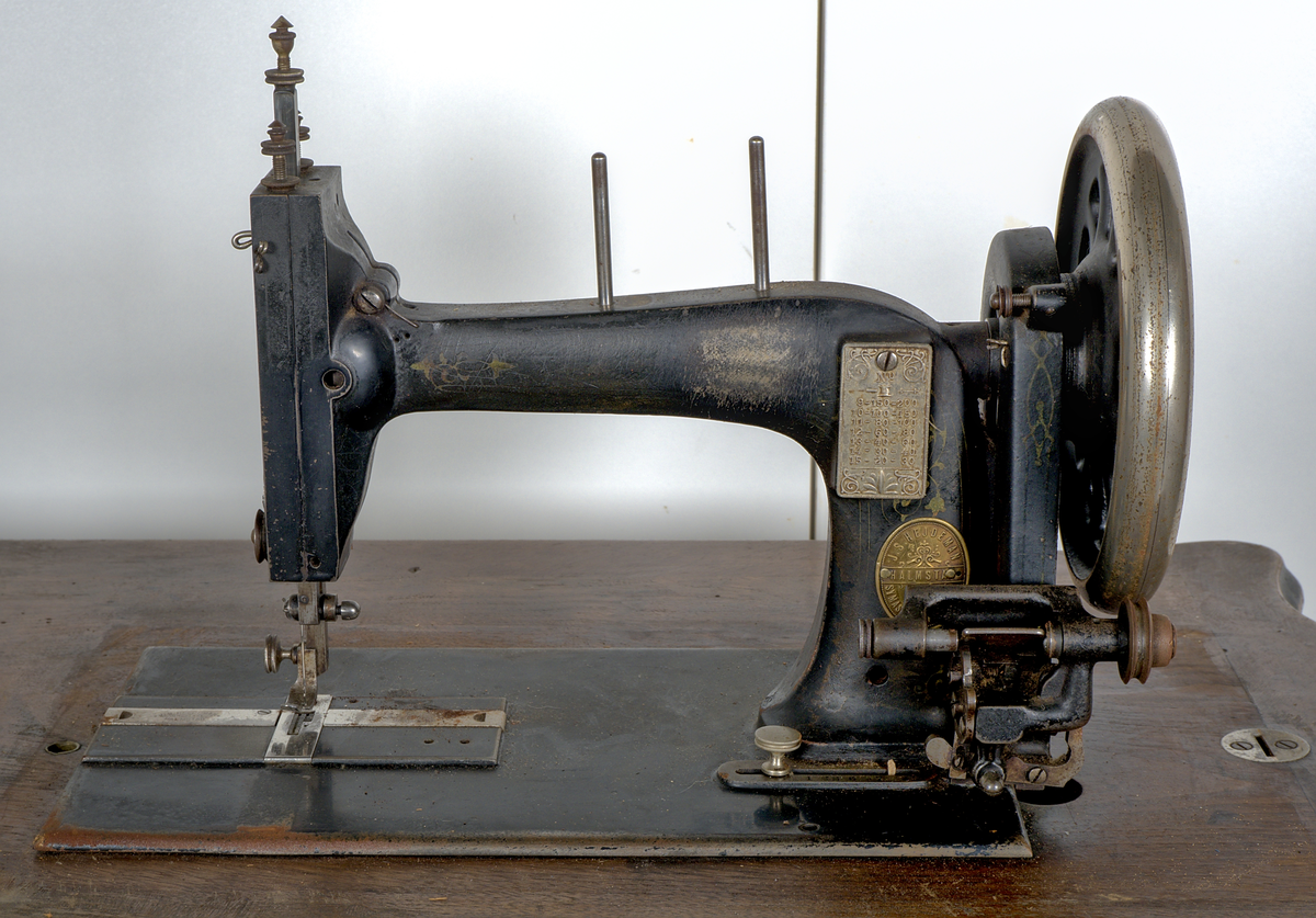 Trampsymaskin med dekorativt gjutjärnsunderrede och en träskiva som arbetsyta.

Svartmålad maskin dekorerad med sirlig ornamentik i guldfärg. På maskinens framsida sitter två märkta plåtar:

1. En referenstabell, för nålar?
2. Signering: "J.S. Hejdeman, Halmstad. Symaskin försäljning".

Maskinen är monterad på en profilerad träskiva av ek, försedd med en måttstock i intarsia på skivans framsida. Under bordet finns en skjutbar tillbehörslåda med låsmekanism. Maskinen skyddas av en rektangulär huv av ek, försedd med fyra dekorativa, svarvade hörnstolpar.

Det svartlackerade gjutjärnsstativet har en dekorativ utformning. På var sida av stativet finns två ovala medaljonger med relieftexten: "J.S. HEJDEMAN, HALMSTAD". De båda benen på höger sida av ställningen är försedda med hjul.