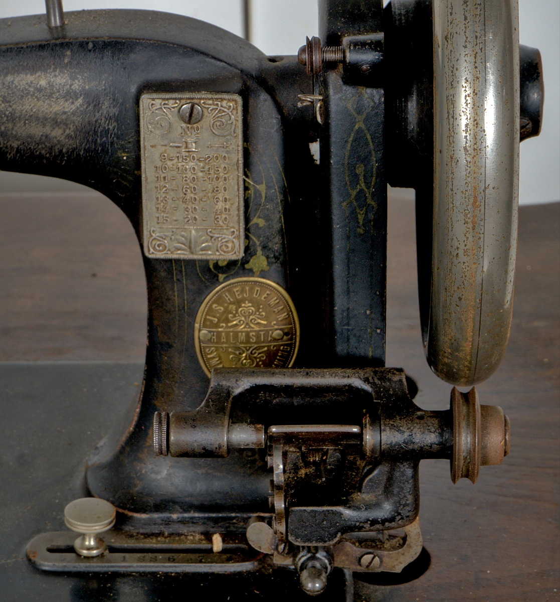 Trampsymaskin med dekorativt gjutjärnsunderrede och en träskiva som arbetsyta.

Svartmålad maskin dekorerad med sirlig ornamentik i guldfärg. På maskinens framsida sitter två märkta plåtar:

1. En referenstabell, för nålar?
2. Signering: "J.S. Hejdeman, Halmstad. Symaskin försäljning".

Maskinen är monterad på en profilerad träskiva av ek, försedd med en måttstock i intarsia på skivans framsida. Under bordet finns en skjutbar tillbehörslåda med låsmekanism. Maskinen skyddas av en rektangulär huv av ek, försedd med fyra dekorativa, svarvade hörnstolpar.

Det svartlackerade gjutjärnsstativet har en dekorativ utformning. På var sida av stativet finns två ovala medaljonger med relieftexten: "J.S. HEJDEMAN, HALMSTAD". De båda benen på höger sida av ställningen är försedda med hjul.