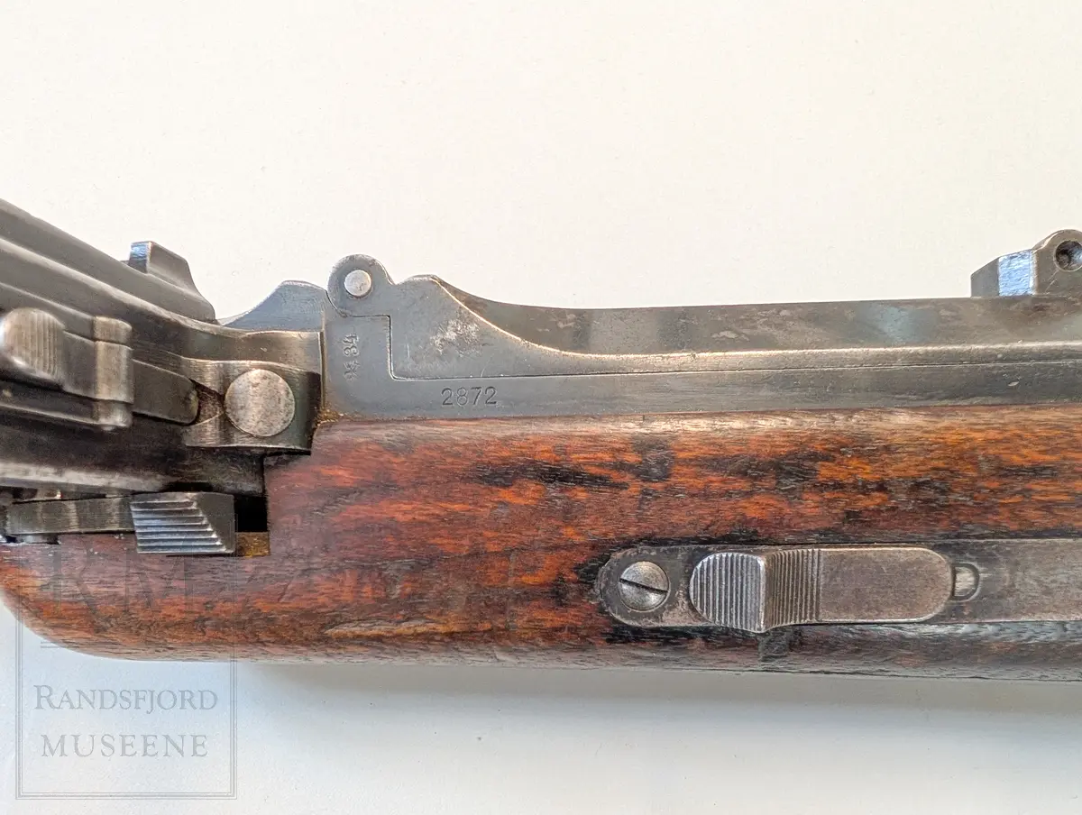 Maskinpistol .Kaliber 9 mm. Parabellum. Magasin: 33 skudd. Munningshastighet 418m/s