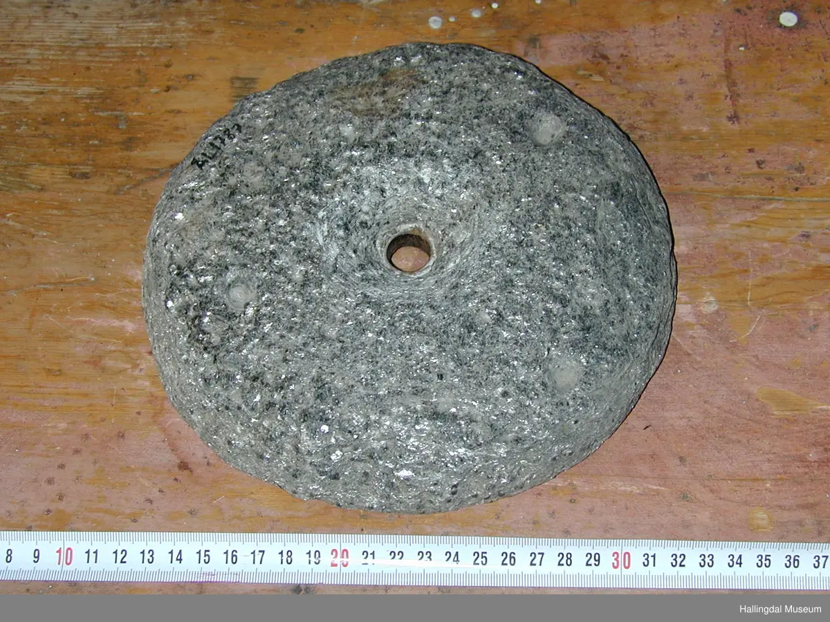Rund stein med rundt hol i midten.