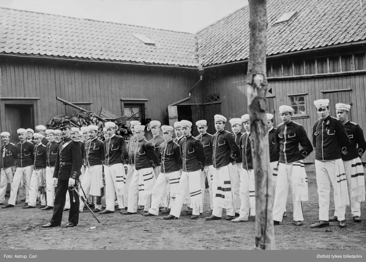 Gruppebilde av turnere i Fredrikshald Turnforening, 1920-tallet. Ukjent sted i Halden.
Konrad Trønnes er med på bildet, opprinnelig fra Koppang i Østerdalen (f. 1885 d. 1957).  Han ble kemner i Halden fra 1934 av. 
Trønnes trente disse:
1919-22: voksne - og herreparti
1924-29: gutte- og herreparti og aspiranter.
Silkesjerfene indikerer graden til turneren: forturner, overturner og viseturner.