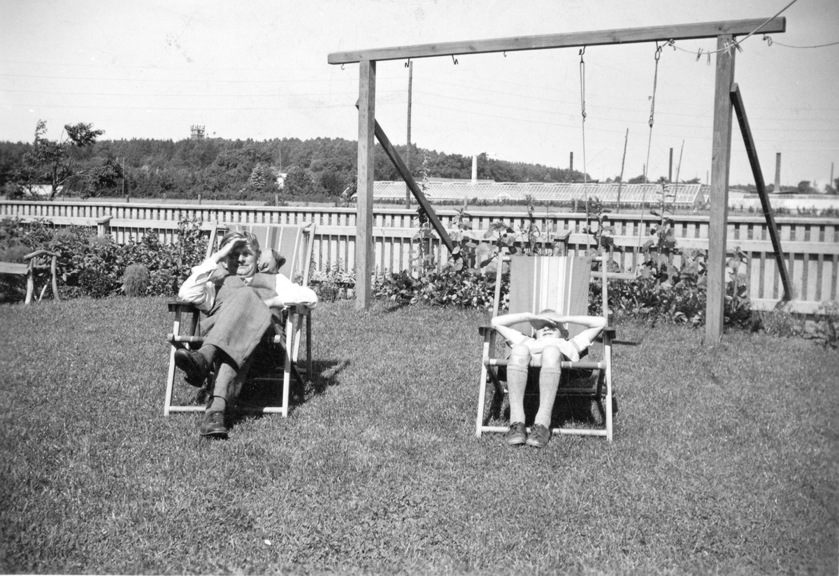 Hos familjen Bossmark på Hedvägen 5 i Varberg. Bild 1 föreställer Eric Johansson och sonen Bengt Bossmark i varsin solstol i trädgården. Här låg de s k barnrikehusen. I bakgrunden ses långa växthus till en handelsträdgård och krönet på Varbergs vattentorn syns på åsen.

Bild 2 är en familjebild med sju personer i en soffa - längst till vänster står sonen Sven Bossmark. Eric och frun Hanna hade nio barn. Utifrån Svens ålder är bilden tagen omkring 1940.