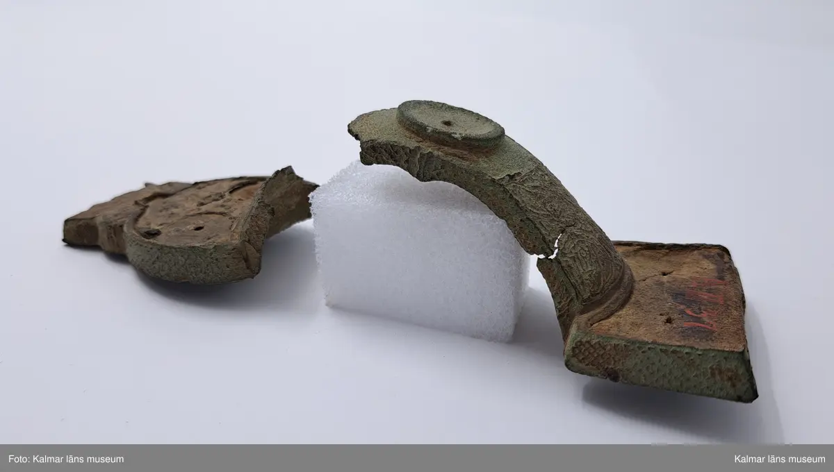 KLM 232. Spänne, ryggknappspänne. Gjutet av brons. Ryggknapp och skiva samt ungefär hälften av nedersta rundeln fattas. Bågen är avbruten. Fyllningen i de fördjupade partierna ligger kvar och täcks delvis av bronsbleck. Spår av förgyllning. På kanterna ornering med rutmönster och på bygeln med slingrande ornament.