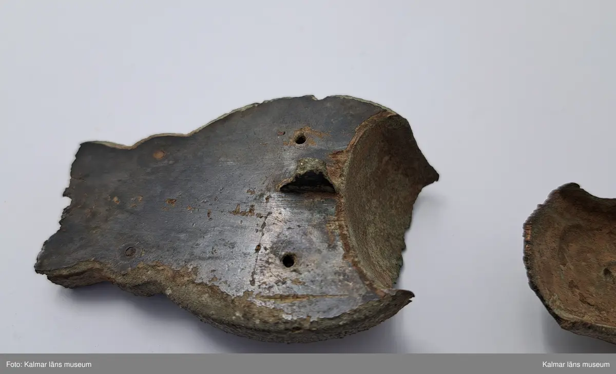 KLM 232. Spänne, ryggknappspänne. Gjutet av brons. Ryggknapp och skiva samt ungefär hälften av nedersta rundeln fattas. Bågen är avbruten. Fyllningen i de fördjupade partierna ligger kvar och täcks delvis av bronsbleck. Spår av förgyllning. På kanterna ornering med rutmönster och på bygeln med slingrande ornament.