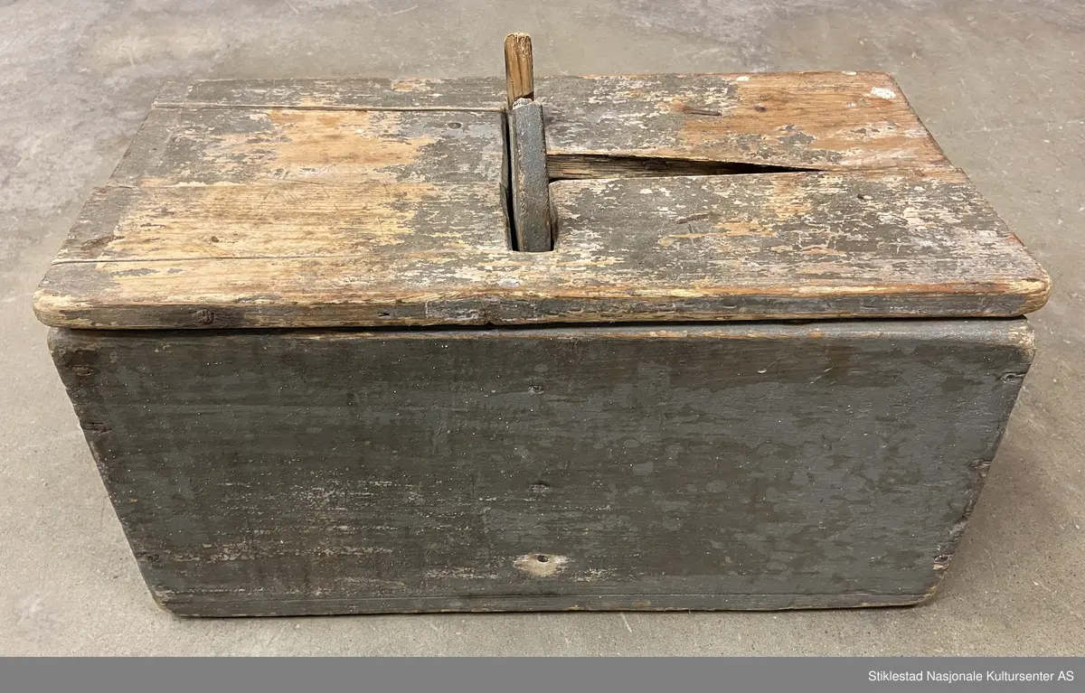 Todelt melkopp (kar) med hank og lokk, grågrønn farge. Svært slitt, sprukket, deler borte.