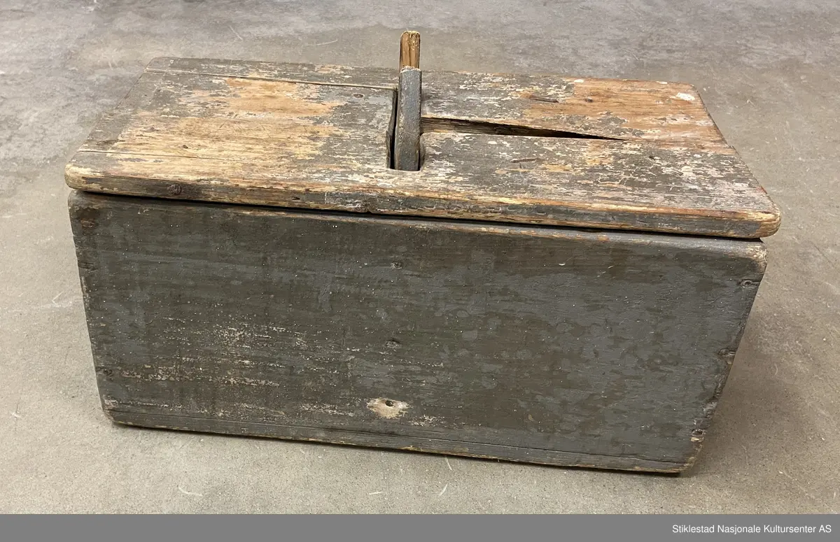 Todelt melkopp (kar) med hank og lokk, grågrønn farge. Svært slitt, sprukket, deler borte.