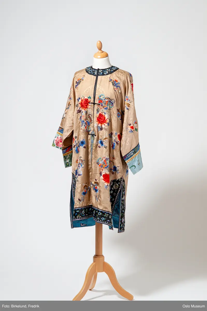 Kimono i gulbeige silkestoff med broderte blomster i ulike farger.