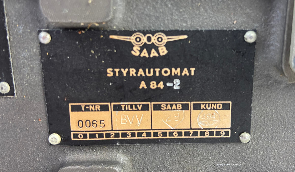 Två styck styrautomater i transportlåda av plåt. En styrautomat har ett genomskinlig plasthölje  och den andra har ett rödaktigt hölje.  Styrautomat A 84-2 och XA 82-2. Lådan har lock med text: "Styrinstrument automat".