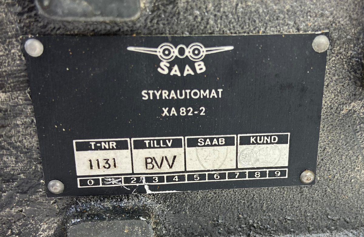 Två styck styrautomater i transportlåda av plåt. En styrautomat har ett genomskinlig plasthölje  och den andra har ett rödaktigt hölje.  Styrautomat A 84-2 och XA 82-2. Lådan har lock med text: "Styrinstrument automat".