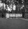 Gymnastikuppvisningen, 25/5 1941. 
Kvinnliga gymnaster tågar in på Värendsvallen, åtföljda av en
kvinnlig ledare i vit dräkt.