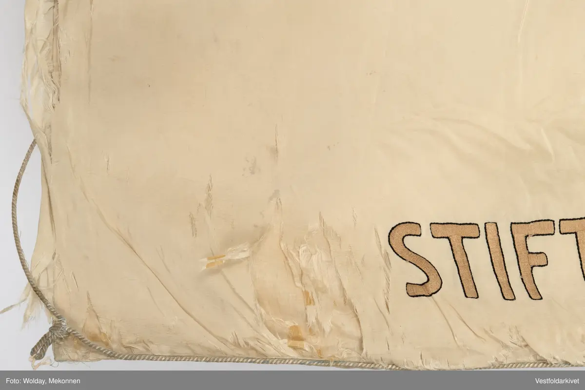 Lys silkefane med bemalt logo og tekst.