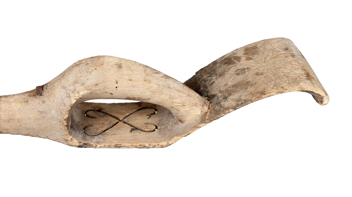 Böjt blad av järn fastnitat utanpå skaftet. Skaft av trä med bygelhandtag och böjd ändplatta. På skyddsskivans plana del två genombrutna med spetsarna mot varandra ställda hjärtan. På ändplattan under handtaget inskuret rund karvsnittsrosett. Andra sidan sträckdekor, ristning för karvsnittsrosett samt "ANO 1846 CAD".

Äldre historik:
En skära är ett verktyg som man skär av säd med. Den är halvcirkelformad med eggen på cirkelbågens insida. Radiellt utåt från cirkelbågens ena ände finns ett handtag, som kan vara av trä. Skäran hålls i den ena handen, och med den andra handen samlar man ihop ett knippe strån som man sedan skär av med skäran. (Wikipedia)