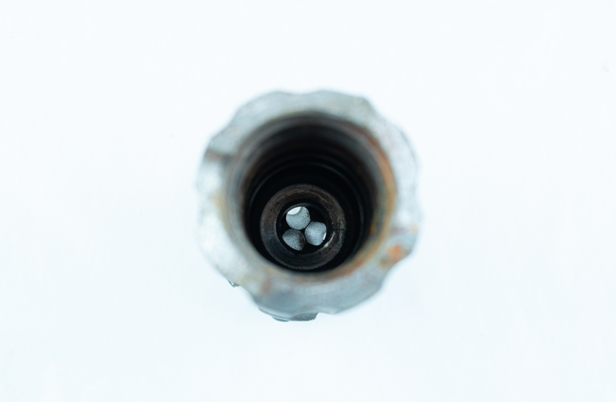 Sylindrisk formet borekrone med riller langs sidene. I ene enden er den tagget. I den andre enden er den noe smalere med et hode på toppen. Hodet er ruglete med tre hull på toppen og et hull på siden. Den har bruksmerker og noe rust. Borekronen ble brukt til gjennomslagssalven i Rossåstunnelen på nye E39 i Lyngdal
