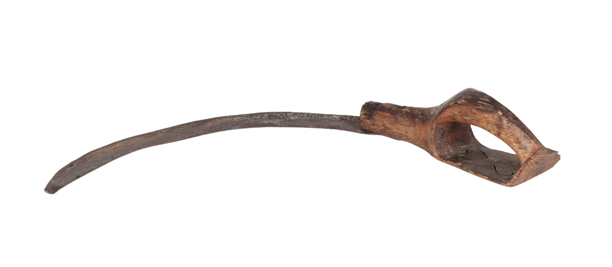 Böjt blad av järn som är fastnitat på skaftet. Skaft av rödmålat trä med bygelhandtag, ändplattan saknas. På andra sidan två genombrutna hjärtan, streckdekor samt på resterande ändplattan "ANO 1845".

Äldre historik:
En skära är ett verktyg som man skär av säd med. Den är halvcirkelformad med eggen på cirkelbågens insida. Radiellt utåt från cirkelbågens ena ände finns ett handtag, som kan vara av trä. Skäran hålls i den ena handen, och med den andra handen samlar man ihop ett knippe strån som man sedan skär av med skäran. (Wikipedia)