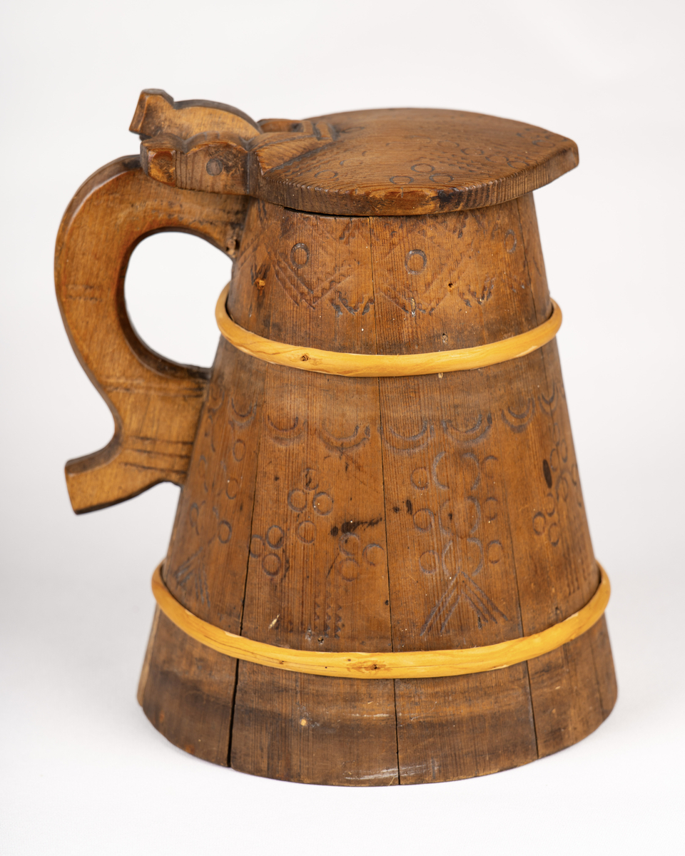 Lagget drikkekanne med hank og lokk. Nyere gjorder. Utvendig svidekor på korpus, hank og lokk. Initialer og årstall skåret ut under bunnen: OHS // ANO 1784.