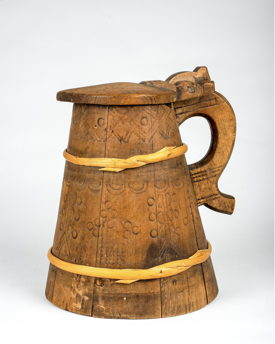 Lagget drikkekanne med hank og lokk. Nyere gjorder. Utvendig svidekor på korpus, hank og lokk. Initialer og årstall skåret ut under bunnen: OHS // ANO 1784.