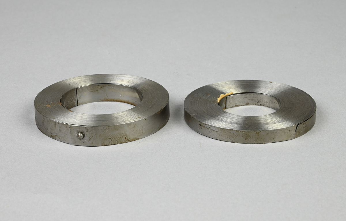 Två prover på härdat bandstål. Tre tillhörande lappar med notering: "Härdat bandstål för måttband. 9,5 x 0,20 mm. resp. 6,35 x 0,165 mm. Tillverkat vid Munkfors bruk, Uddeholms AB."