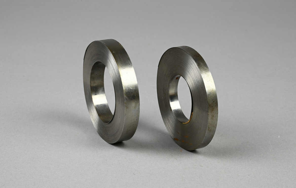 Två prover på härdat bandstål. Tre tillhörande lappar med notering: "Härdat bandstål för måttband. 9,5 x 0,20 mm. resp. 6,35 x 0,165 mm. Tillverkat vid Munkfors bruk, Uddeholms AB."