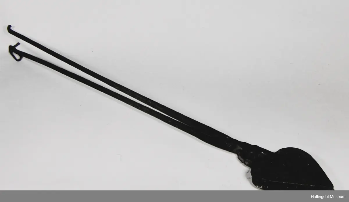 Kvar plate er eit hjarta. Endar i ei firkanta plate øvst, til denne er handtaket festa. Handtaka kryssar kvarandre like ovafor jarnet, festa til kvarandre med gjennomgåenade nagle.