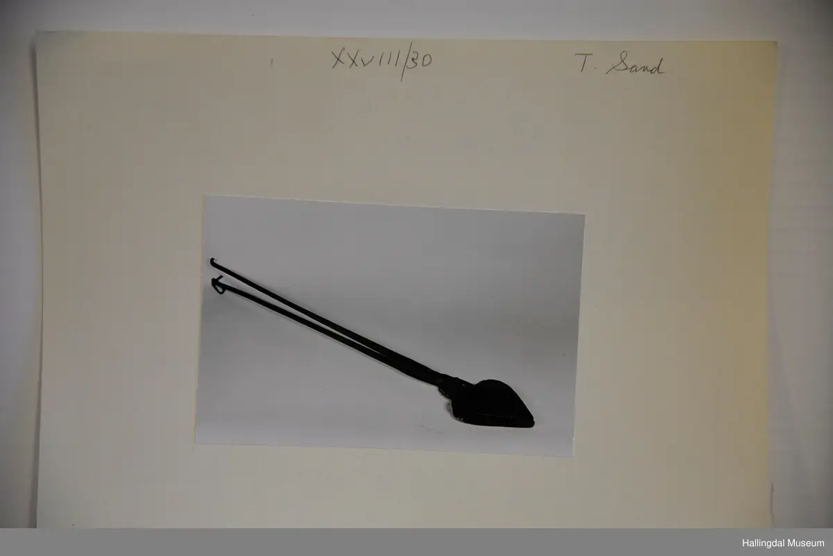 Kvar plate er eit hjarta. Endar i ei firkanta plate øvst, til denne er handtaket festa. Handtaka kryssar kvarandre like ovafor jarnet, festa til kvarandre med gjennomgåenade nagle.