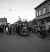 Studenterna, 3/6 1941. En kvinnlig student körs på lövad kärra fram utmed Storgatan (vid P.N. Perssons hörna). I bakgrunden ser man bl a dåv. Riksbankens hus vid Stortorget.