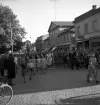Studenterna, 4/6 1941. Studenter och anhöriga m.fl. är på väg uppför Kungsgatan. I bakgrunden skymtar bl a dåv. järnvägsstationen och kupolen till dåv. Växjö Högre Allmänna Läroverk.