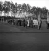 Svenska Flaggans dag, 6/6 1941. Ett antal unga män och kvinnor i studentmössa m.m.,  har ställt upp sig för parad på Värendsvallen. 

Troligen gymnasistföreningen från Växjö Högre Allmänna Läroverk.