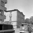 Vy från Klostergatan i Linköping mot fastigheten Drottninggatan 32. En av flertalet ursprungliga hus utmed Drottninggatan som fått skatta för ny bebyggelse. Foto 1965.