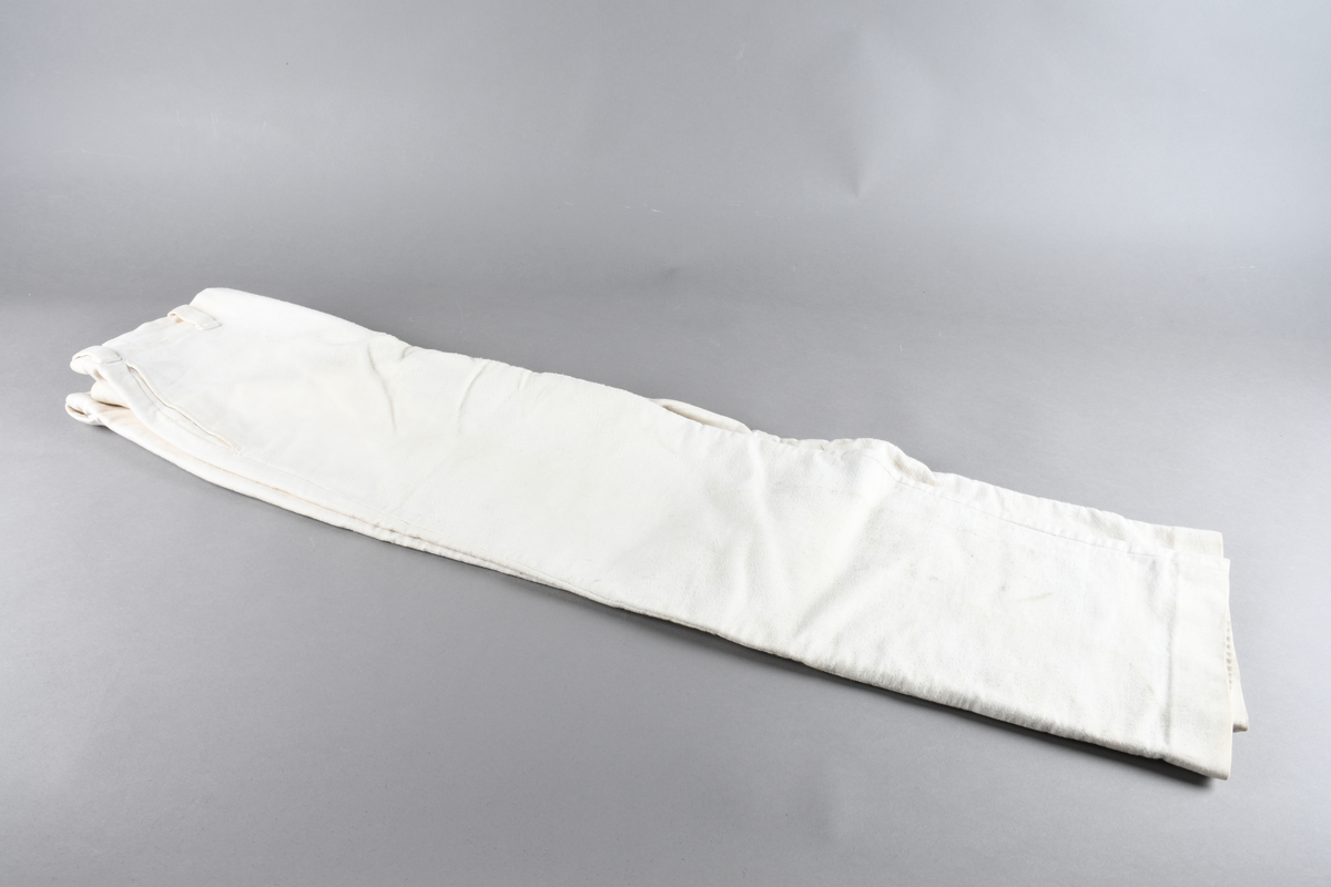 Hvit uniformsbukse med hemper til belte. Høyt liv