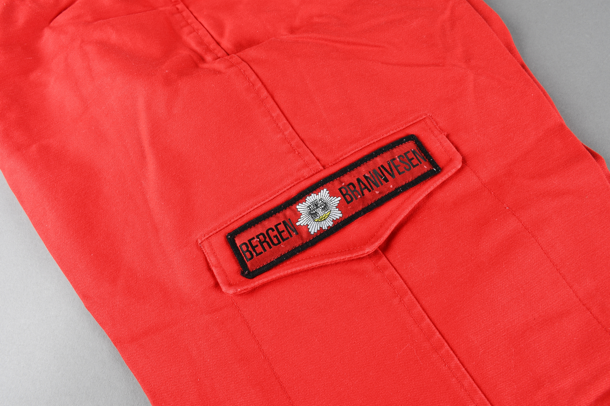 Rød uniformsbukse med glidelås i front og lommer på bein og bakside.